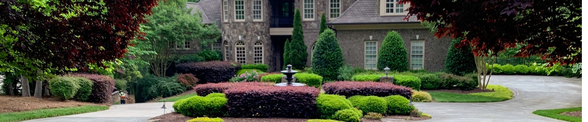 Estate in Raleigh, NC with a ECM Landscaping and Lawn Care employee finishing up a lawn service.