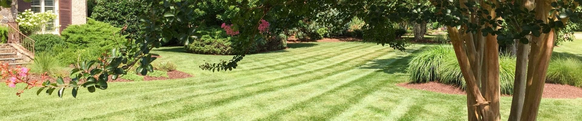 Professionally mowed grass with stripes in it and lots of landscaping beds.