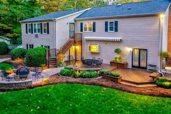 Back of home in Raleigh with a deck, landscaping, and fire pit.